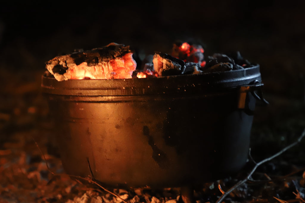 a dutch oven cooking over a wood fire in the wilderness