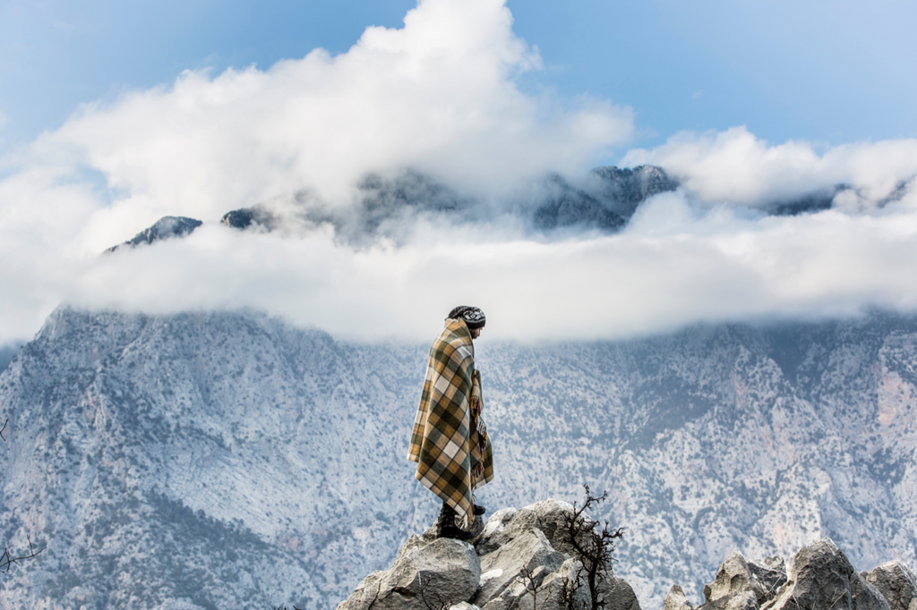 a camper standing on a mountian with a wool blanket on